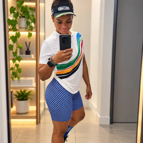 Patrícia com camiseta branca listrada nas cores do Time Brasil e viseira, foto no espelho